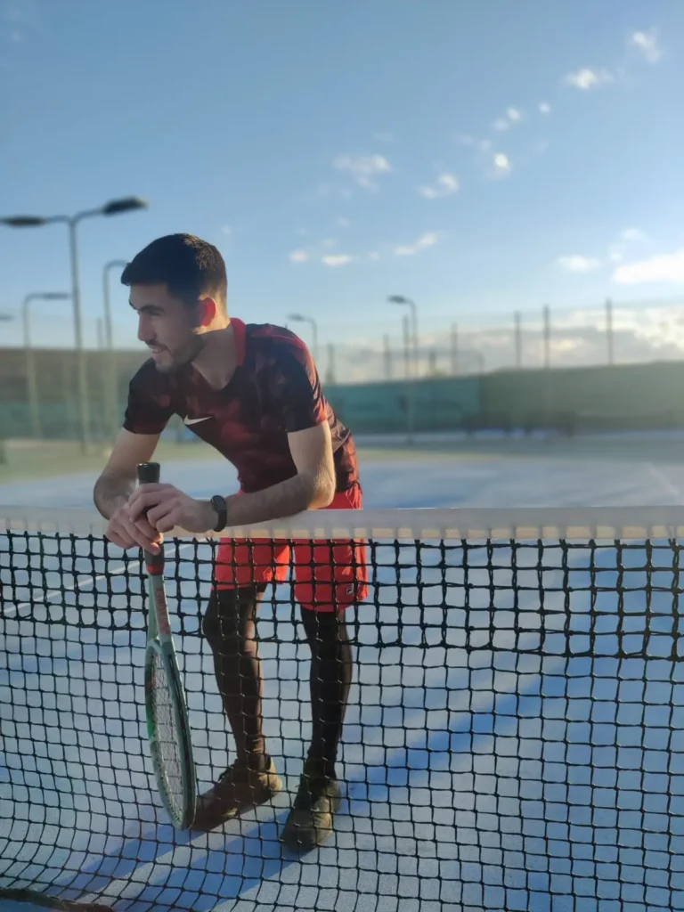 Tennis Player on Hard Surface Tennis Court Leaning on Net-min